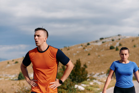 A couple dressed in sportswear runs along a scenic road during an early morning workout, enjoying...