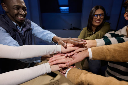 Top view of diverse coworkers business people joining hands together over a wooden office desk, symbolizing teamwork, unity, collaboration, and support in a modern workplace.の写真素材