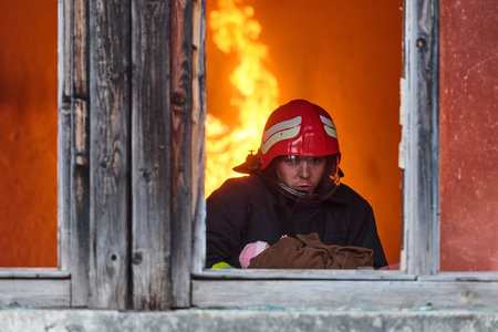 Firefighter rescuing a baby from burning building, fireman in action saving child, emergency...