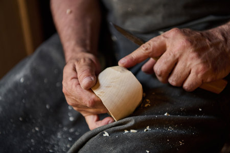 Close up of craftsman hands using knife to carve wood, woodworking process, handmade craft, wood carving, creative hobby, carpentry, DIY project, art, skill, detail shotの写真素材