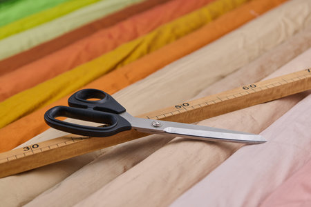 Tailoring tools, scissors and wooden ruler on colorful fabrics, textile industry concept, sewing...