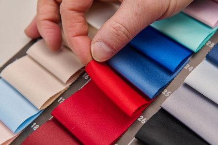 Hand selecting colorful satin ribbon swatches, material sample palette for fashion design, textile...