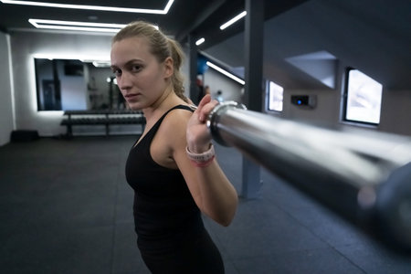 Strong woman lifting weights in a gym showcasing determination and focus during a workout session in...
