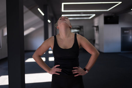 Young woman exercises in a gym, showing determination and focus during a workout session in the...