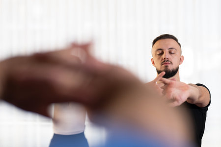 Man stretching his arms forward during a fitness or rehabilitation class indoors. Concept of focus,...