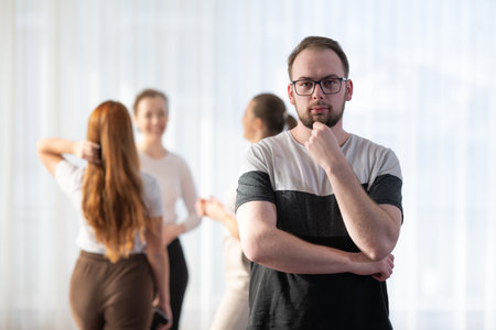 Portrait of a young man wearing glasses while standing with his colleagues in the background.の写真素材