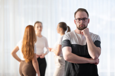 Portrait of a young man wearing glasses while standing with his colleagues in the background during a business meeting.の写真素材