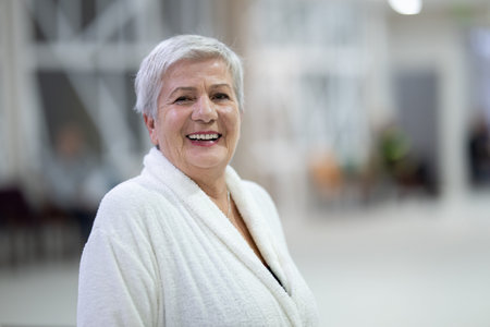 Portrait of a senior woman wearing a white bathrobe at a wellness center, symbolizing relaxation,...
