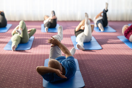 Instructor leading a diverse group of people during a fitness training session with stretching...
