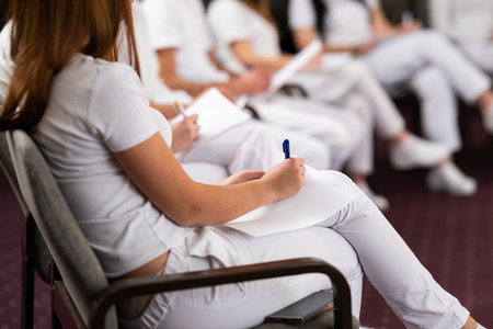 Close up of a student holding a pen and writing notes in a notebook during a professional training...