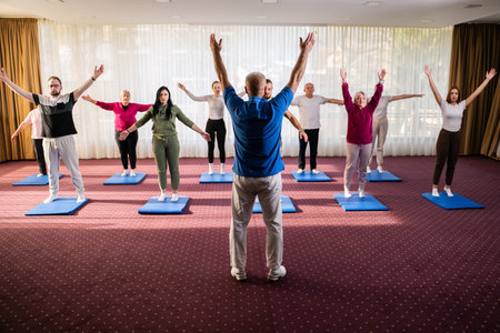 Instructor leading a diverse group of people during a fitness training session with stretching...