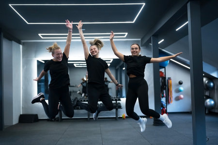 Group of women joyfully jump in a gym during a fitness class in the afternoonの写真素材