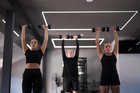 Women lifting weights in a modern gym during a fitness classの写真素材