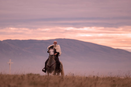 A majestic Viking chieftain on a dappled grey horse, clad in a fur cloak, surveys a desolate,...