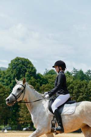 Equestrian sport, horse and rider in dressage competition, woman riding horse in outdoor arena, training and performance, equine event, sunny day, natural light, action shot.の写真素材