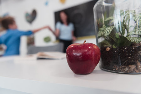 A close-up photo of a bottle containing a green plant and a ripe apple next to the bottleの写真素材