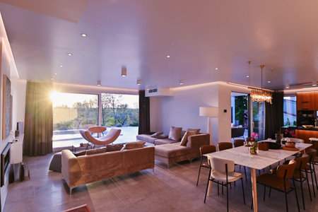 Modern luxury living room interior at sunset. Open-plan space featuring beige sofas, marble dining...
