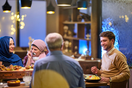 Families share iftar meals together during Ramadan in a cozy restaurant setting with warm lights and...