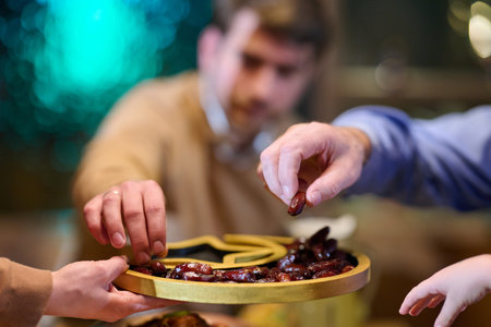 Family members share dates during iftar meal while observing Ramadan traditions at home in the...
