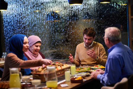 Gathering of family for iftar dinner during Ramadan in a cozy restaurant with rain on the windowの写真素材