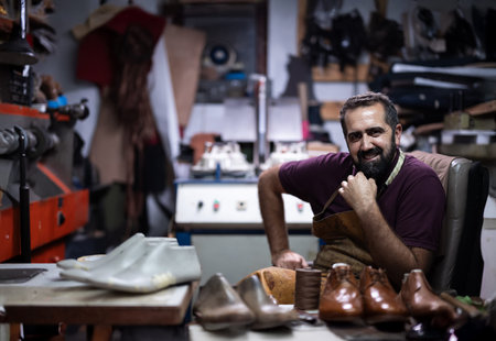 Portrait of a cobbler in his workshop, crafting leather shoes and resting relaxedの写真素材