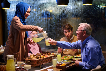 Muslim family sharing iftar meal together in a restaurant during Ramadan with traditional decorationsの写真素材