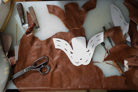 Leather crafting studio with mask templates, tools, and brown leather on a worktable