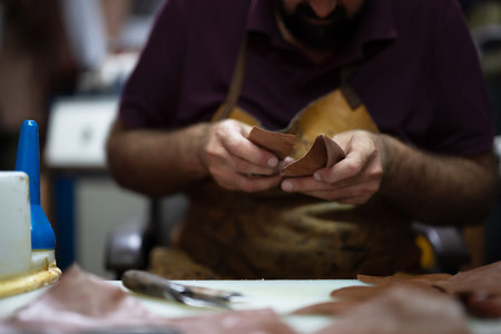 Leather craftsman at work shaping pieces into wallets in a busy workshop