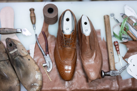 Cobblers workbench with leather shoes, tools, and sewing materials in a detailed workshop for...