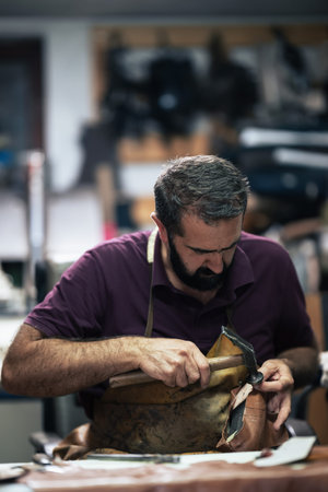 Cobbler at work repairing a leather boot with a hammer in a busy workshop