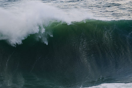 Majestic curling ocean wave with green lip and spray in a powerful seascape for stock use