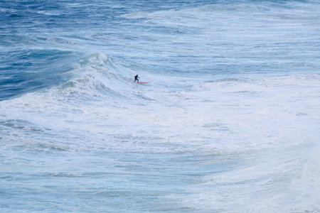 Surfer rides a powerful ocean wave from an aerial view on a red boardの写真素材