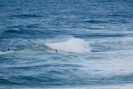 Surfers riding powerful ocean waves during a bright day, dynamic water sport actionの写真素材