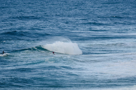 Surfer riding a wave as spray erupts in a vast blue ocean
