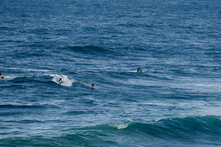 Surfers ride large blue ocean waves in an energetic open-sea scene of sport and motionの写真素材