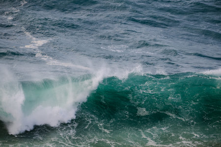 Powerful turquoise ocean wave curling toward shore with spray and foamの写真素材