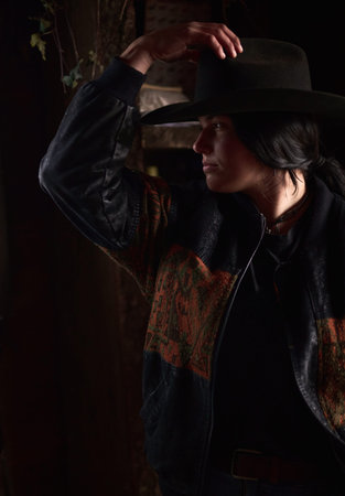 Cowgirl in Wide-Brim Hat Adjusting Her Hat in a Rustic Ranch Setting