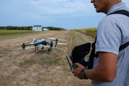 Drone pilot operates controller in a farmland field with a ground drone ready for flight