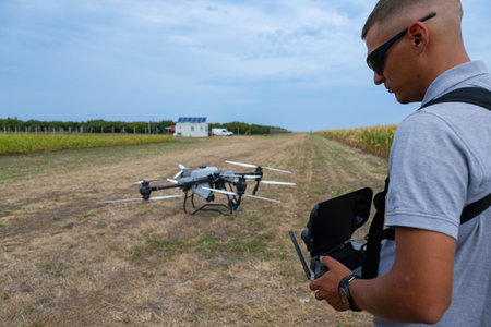 Drone pilot operating handheld controller in open field with quadcopter ready to flyの写真素材
