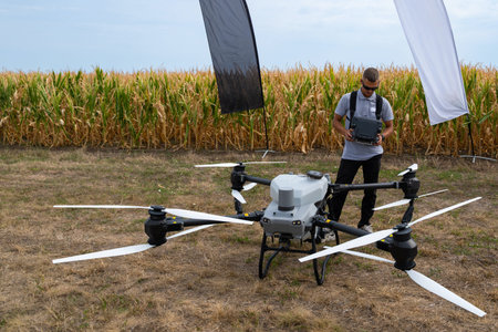 Drone operator tests aerial drone in a cornfield with banners and equipment in open fieldの写真素材
