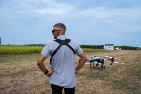 Man with a drone on a dry field watches the ground drone ready for aerial monitoringの写真素材