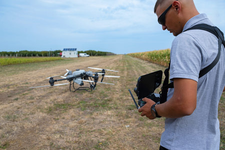 Drone operator outdoors with field drone on farm using remote controller for farming technologyの写真素材