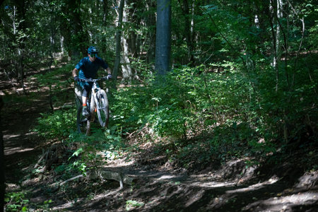 Mountain biker jumps through a forest trail on a mountain bike during a sunny day adventure