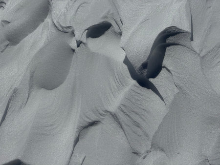 Abstract snow drifts and textured winter patterns with deep shadows and wind-sculpted shapes
