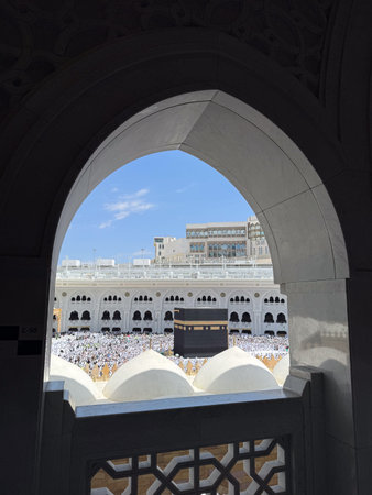 View of the Kaaba and pilgrims in Masjid al-Haram framed by an arched window in Mecca