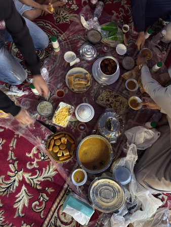 Realistic top view photograph of a traditional Arab family gathering around the table while...