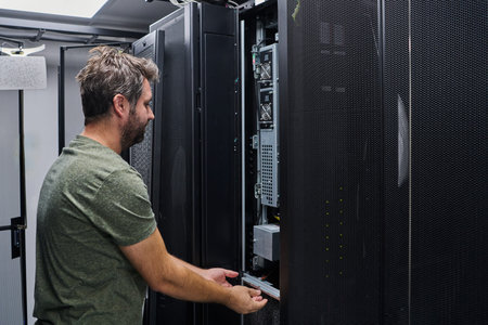IT technician performing server maintenance in a data center rack during routine equipment...