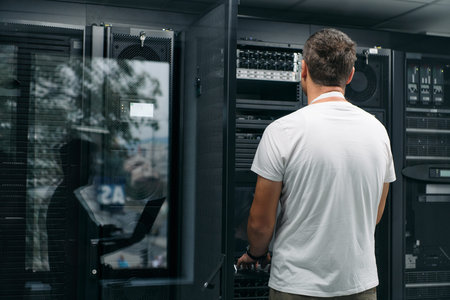 Data center technician checks server hardware in a modern server room for network maintenance and...