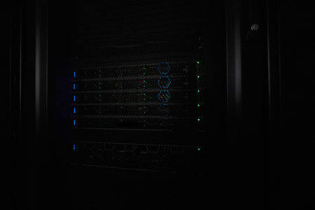 Server rack with illuminated network hardware and blinking LEDs in a dark data center