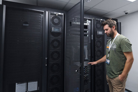 IT technician inspecting server rack in a modern data center performing maintenance and monitoring...